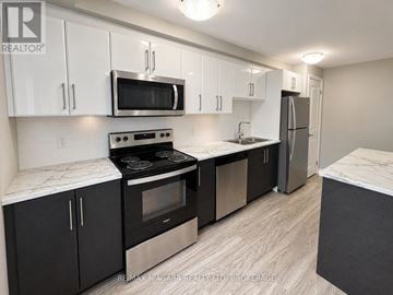 St. Catharines (Downtown) multi-family for rent - A kitchen with black cabinets and stainless steel appliances.
