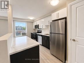 St. Catharines (Downtown) multi-family for rent - A kitchen with a refrigerator, microwave, and oven.