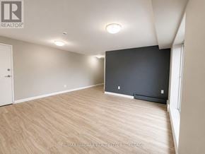 St. Catharines (Downtown) multi-family for rent - A spacious room with wooden flooring and a large window.