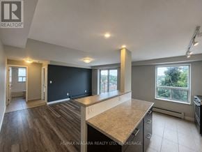 St. Catharines (Downtown) multi-family for rent - A spacious room with a kitchen area and a large window.