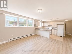 St. Catharines (E. Chester) multi-family for rent - A spacious kitchen and living room with light wood flooring and white cabinetry.