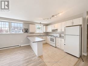 St. Catharines (E. Chester) multi-family for rent - A kitchen with white appliances and cabinets.