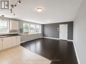 St. Catharines (E. Chester) multi-family for rent - A spacious room with a kitchen area and a large window.