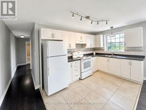St. Catharines (E. Chester) multi-family for rent - A kitchen with white appliances and cabinets.