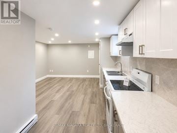 St. Catharines (E. Chester) multi-family for rent - A kitchen with a white counter top and wooden floors.