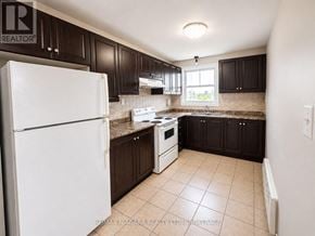 St. Catharines (E. Chester) multi-family for rent - A kitchen with white appliances and brown cabinets.