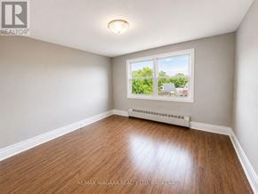 St. Catharines (E. Chester) multi-family for rent - A room with a window showing a view of a house and trees outside.