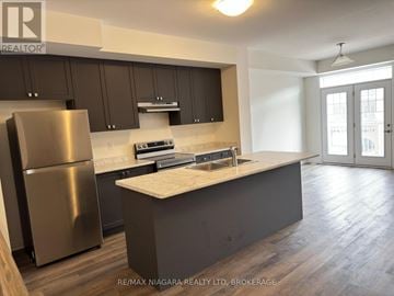 Welland (Dain City) townhouse for rent - A modern kitchen with dark brown cabinets and a stainless steel refrigerator.