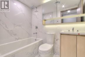 Toronto (Waterfront Communities) condo for rent - A white bathroom with marble walls and a wooden cabinet.