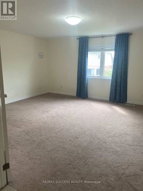 Brantford apartment for rent - A room with a carpeted floor and a window with blue curtains.