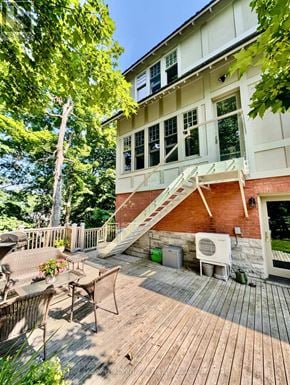 Ottawa apartment for rent - A wooden deck with a white table and chairs is in front of a house.