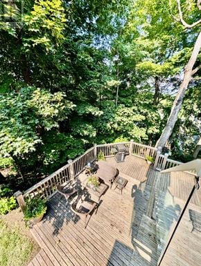 Ottawa apartment for rent - A wooden deck with a table and chairs surrounded by trees.
