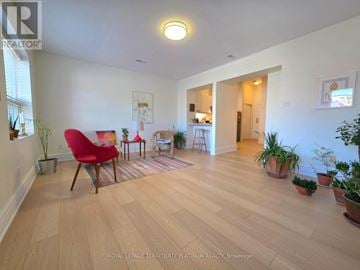 Toronto (Little Portugal) multi-family for rent - A living room with a red chair and wooden floors.