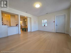 Toronto (Little Portugal) multi-family for rent - A spacious room with wooden flooring and white walls.