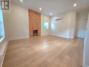 Toronto (Little Portugal) multi-family for rent - A room with wooden flooring and a brick wall.