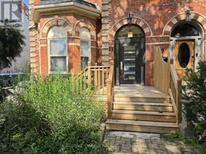 Toronto (Little Portugal) multi-family for rent - A red brick house with a wooden front porch.