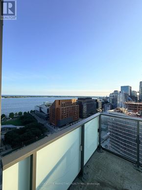 Toronto (Waterfront Communities) condo for rent - A balcony overlooks a cityscape with buildings and a body of water.