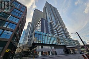 Toronto (Waterfront Communities) condo for rent - A modern building with a glass facade stands tall in a cityscape.