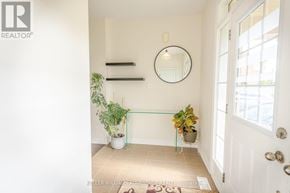 Brampton (Credit Valley) apartment for rent - A hallway with a white door, a mirror, and a plant on a glass table.