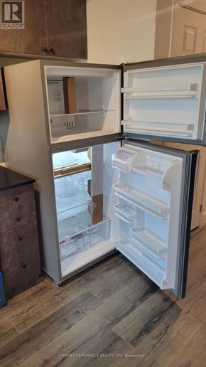 Brantford condo for rent - A refrigerator with its door open showing the empty shelves.