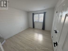 Barrie (Innis-Shore) apartment for rent - A room with wooden flooring and a window with curtains.