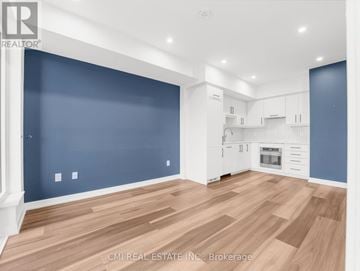 Kitchener condo for rent - A spacious kitchen with white cabinets and a wooden floor.