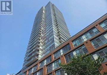 Toronto (Waterfront Communities) condo for rent - A tall glass building with the name ANGLOARD HEALTH BROKERAGE CORP on the side.