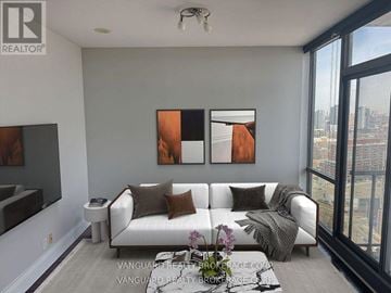 Toronto (Waterfront Communities) condo for rent - A living room with a white couch and two paintings on the wall.