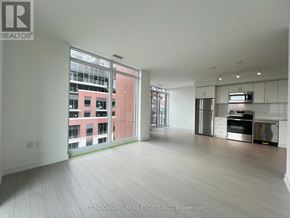 Toronto (Humber Heights) condo for rent - A spacious, empty apartment with a kitchen area and a view of a cityscape through the windows.