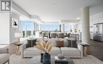 Mississauga (Clarkson) condo for rent - A modern living room with a large grey sofa and a vase with dried flowers on the coffee table.