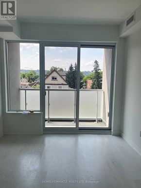 Hamilton (Kirkendall) condo for rent - A room with a sliding glass door leading to a balcony with a view of houses and trees.