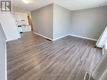 Orangeville apartment for rent - A spacious room with wooden flooring and white walls.