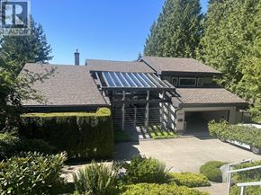West Vancouver apartment for rent - A house with a garage and a driveway is surrounded by greenery.