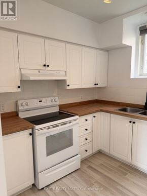 Russell apartment for rent - A white kitchen with wooden countertops and a stove top oven.
