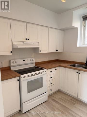 Russell apartment for rent - A white kitchen with wooden countertops and a stove top oven.