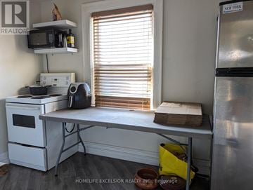 Oshawa (O'neill) apartment for rent - A small kitchen with a refrigerator, microwave, and a window with blinds.