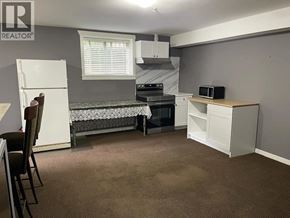 Maple Ridge apartment for rent - A bedroom with a bed, a desk, and a refrigerator.