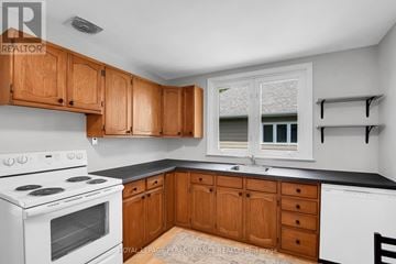 Ottawa apartment for rent - A kitchen with wooden cabinets and a white stove top oven.