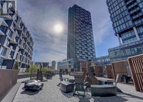 Toronto (Banbury-Don Mills) condo for rent - A sunny day in a modern city with tall buildings and a public space with benches and tables.