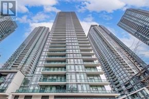 Mississauga (City Centre) condo for rent - A tall residential building with a glass facade stands under a blue sky.