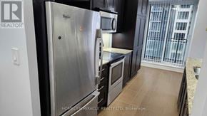 Mississauga (City Centre) condo for rent - A kitchen with a stainless steel refrigerator and black cabinets.