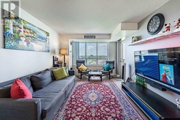 Toronto (West Humber-Clairville) condo for rent - A living room with a grey couch, a red cushion, a patterned rug, a flat screen TV and a painting on the wall.