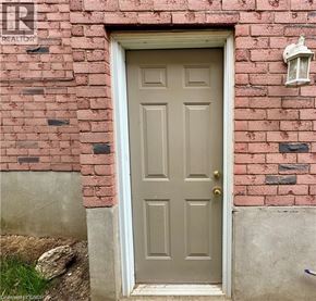 Cambridge apartment for rent - A grey door with a gold handle is set in a brick wall.