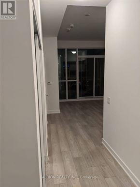 Toronto (Moss Park) condo for rent - A hallway with wood flooring and white walls.