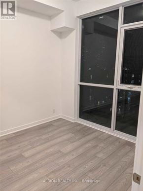 Toronto (Moss Park) condo for rent - A room with a view of the city at night through the windows.