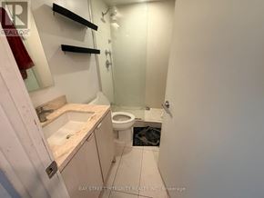 Toronto (Waterfront Communities) condo for rent - A white bathroom with a toilet, sink, and mirror.
