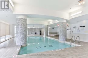 Toronto (Willowdale East) condo for rent - A large indoor swimming pool with a wooden floor and white pillars.