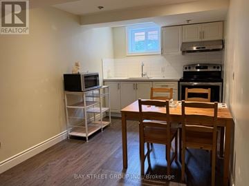 Toronto (Bathurst Manor) apartment for rent - A kitchen with a table and chairs in the foreground and a microwave on the counter.