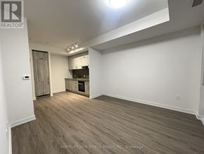 Toronto (Banbury-Don Mills) condo for rent - A spacious room with wooden flooring and white walls, featuring a kitchenette with a sink and cabinets.