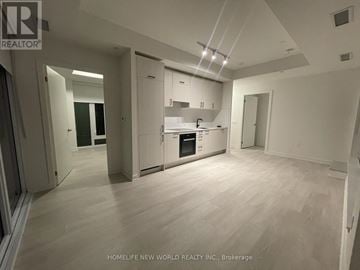 Toronto (Banbury-Don Mills) condo for rent - A spacious kitchen with white cabinets and a wooden floor.